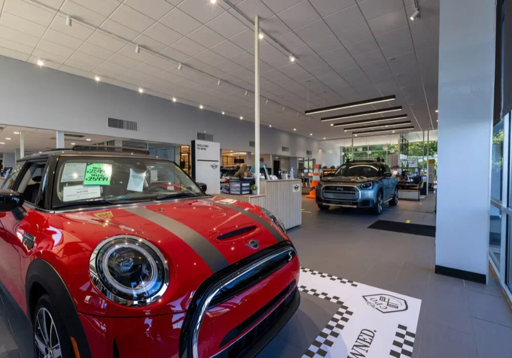 Interior of the Flow MINI dealership in Winston-Salem. There are two Mini Cooper cars parked inside…